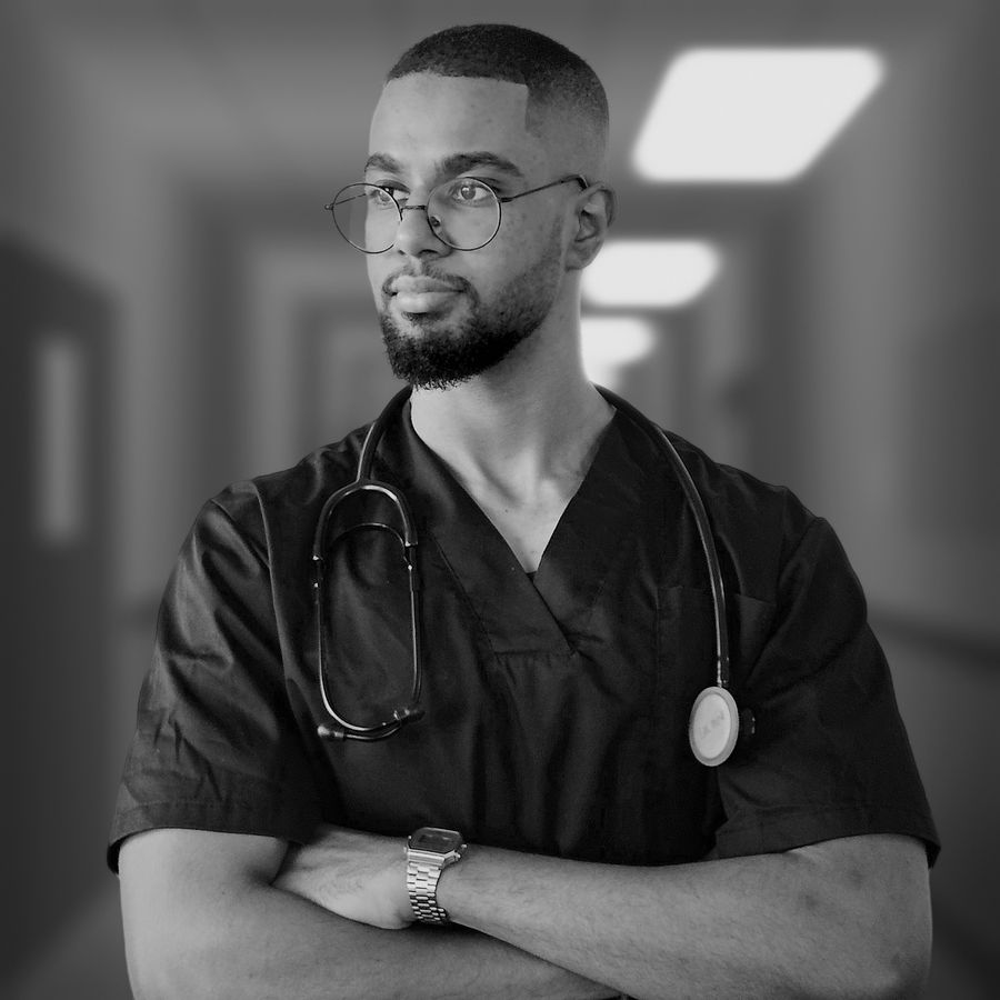 Monkai in black scrubs with a stethoscope, arms crossed